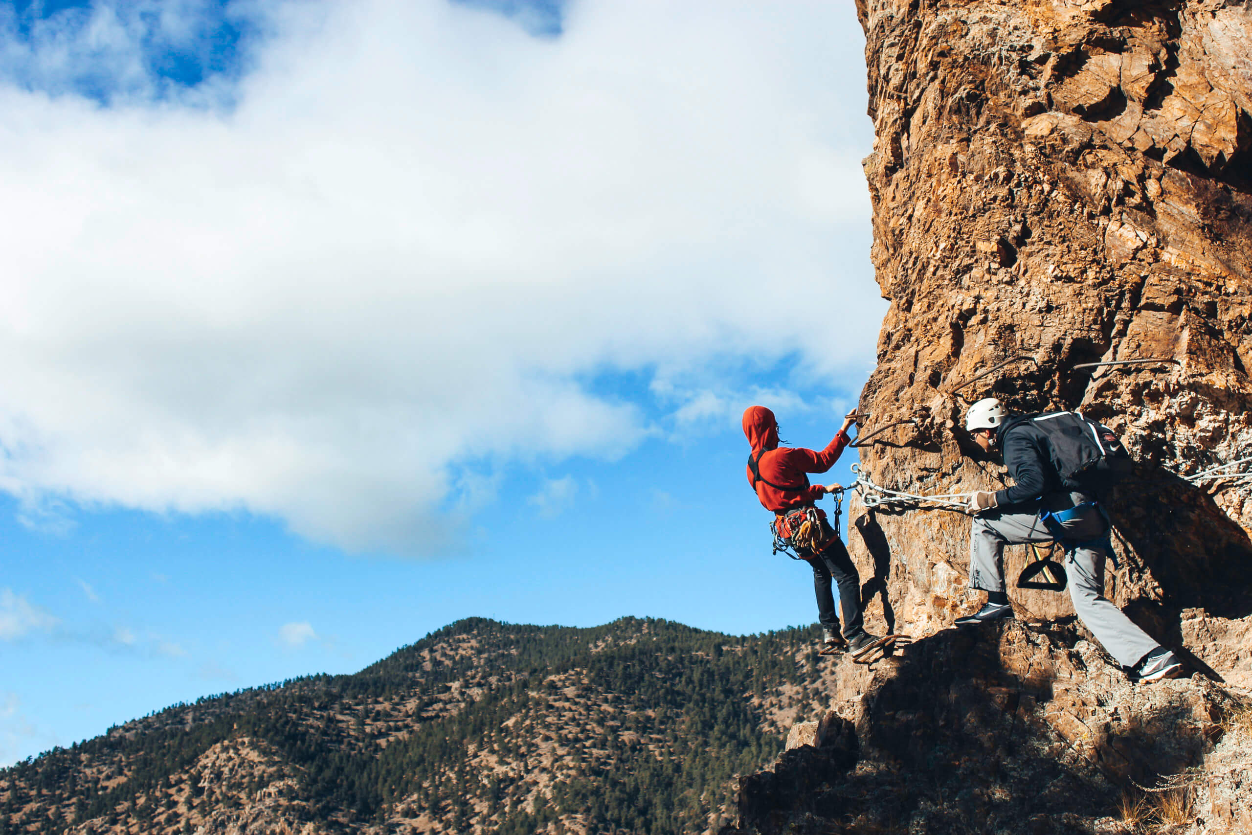 two people scaling a rock face