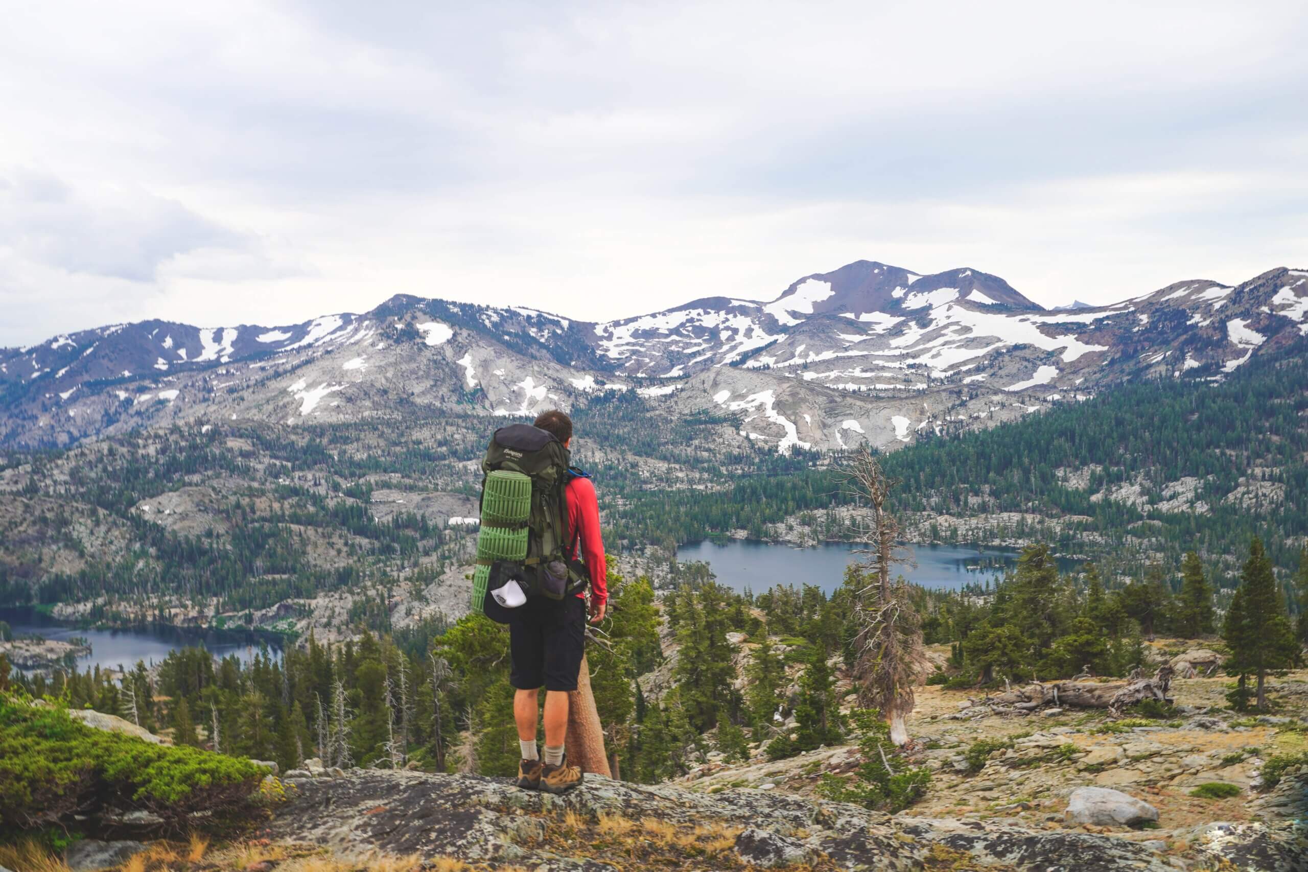 man staring off into distance with pack and camping gear